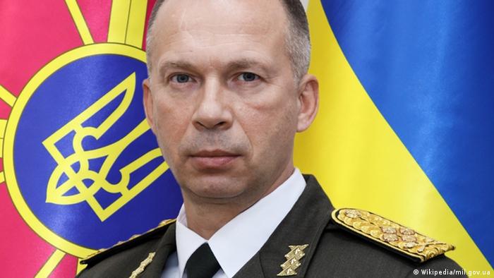 Porträt von Generaloberst Oleksandr Syrskyj, Chef der ukrainischen Landstreitkräfte, für einer Flagge in den ukrainischen Landesfahnen und einem Wappen