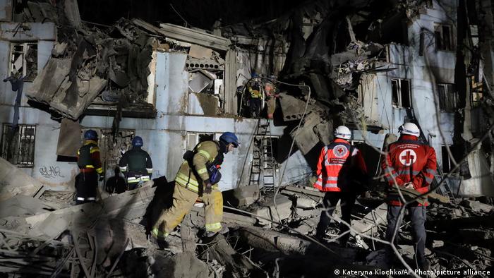 Bomberos y rescatistas inspeccionan el edificio destruido por el ataque ruso.