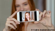 21/11/2015 Portrait of a happy redhead woman making selfie photo on smartphone