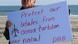 A man holding a sign that reads "Protect our whales from ocean turbine noise"