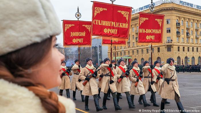 Marschierende Soldaten in historischen Uniformen, rote Fahnen mit Aufschrift Stalingrader Front