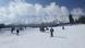 A group of skiers on a slope with mountain tops in the background A group of skiers on a slope with mountain tops in the background