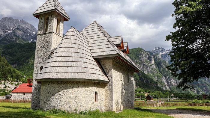 Eine Kirche steht vor einem Bergpanorama, Albanien
