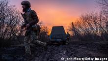 BAKHMUT, UKRAINE - MARCH 04: A soldier from a Ukrainian assault brigade walks across a muddy road used to transport and position British made L118 105mm Howitzers on March 04, 2023 near Bakhmut, Ukraine. Soldiers said they received training on the towed light guns in Germany last summer but took possession of the artillery pieces, sent by the UK, in January, 2023. (Photo by John Moore/Getty Images)