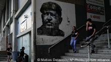 04/03/2023 People walk past near a mural of the late Venezuelan President Hugo Chavez in Caracas, Venezuela, Friday, March 3, 2023. (AP Photo/Matias Delacroix)
