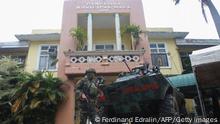 An armed member of the police Special Action Force (SAF) stands guard in front of the municipal hall in Pamplona town in Negros Oriental on March 5, 2023, a day after provincial governor Roel Degamo and eight others were killed in a mass shooting. (Photo by Ferdinand Edralin / AFP) (Photo by FERDINAND EDRALIN/AFP via Getty Images)