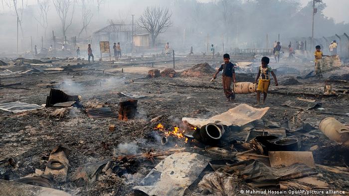 In den Resten der verbrannten Bambushütten bergen Flüchtlingskinder Gasflaschen 