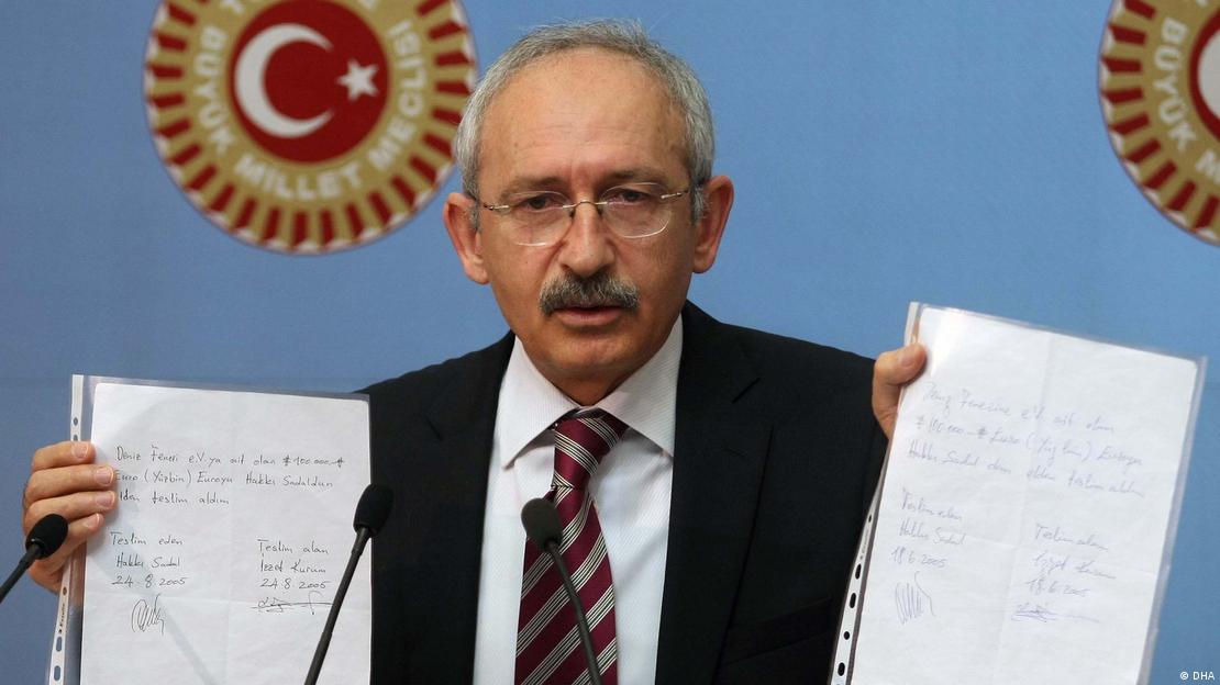 Kemal Kilicdaroglu holding up two sheets of paper that appear to be evidence