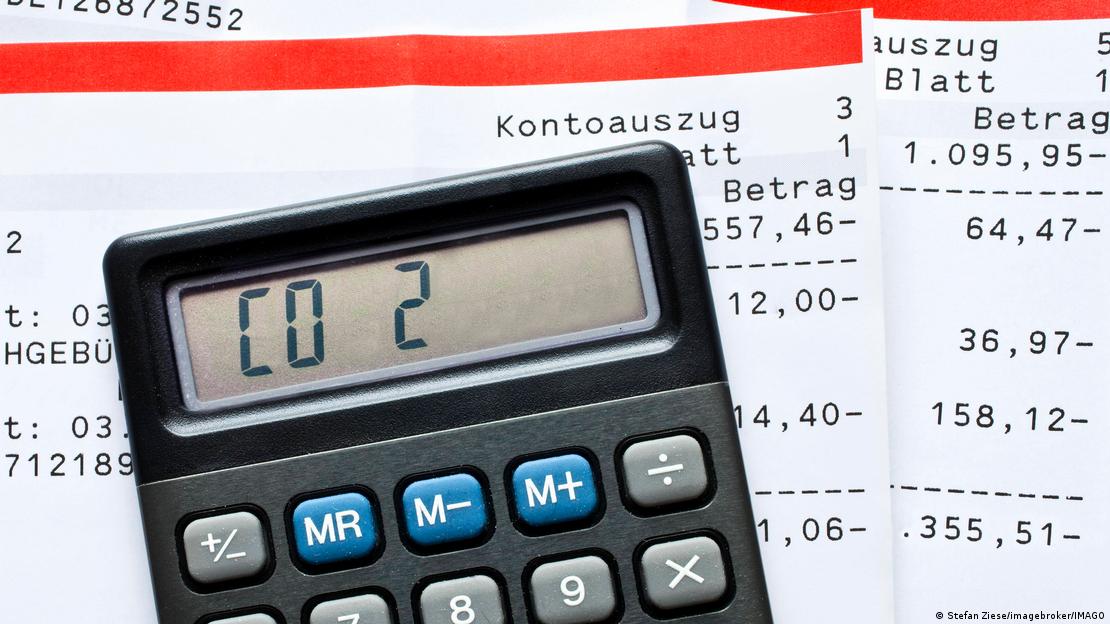 Calculadora com "CO₂" indicado na tela, repousada sobre extratos bancários. Calculadora com "CO₂" indicado na tela, repousada sobre extratos bancários.
