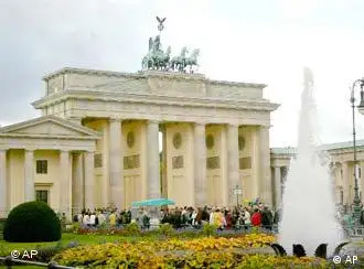 Menschen vor dem Brandenburger Tor, im Vordergrund Blumen und ein Springbrunnen