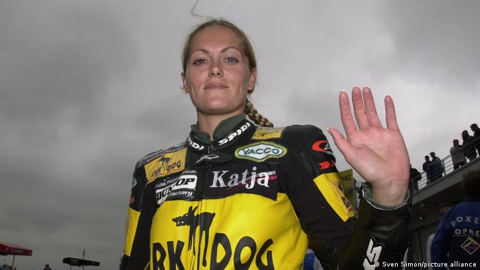 Motorrad-Rennfahrerin Katja Poensgen im Rennanzug winkt in die Kamera