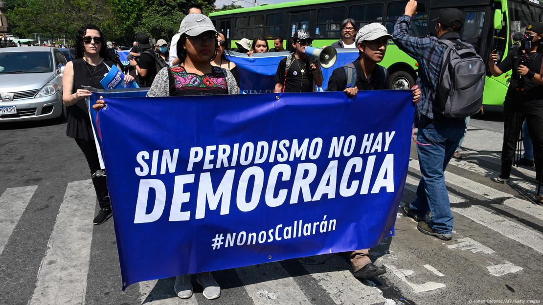 Periodistas llevan un cartel que dice: "Sin periodismo no hay democracia - #NOnosCallarán", delante de la Corte Suprema de Justicia de Guatemala.