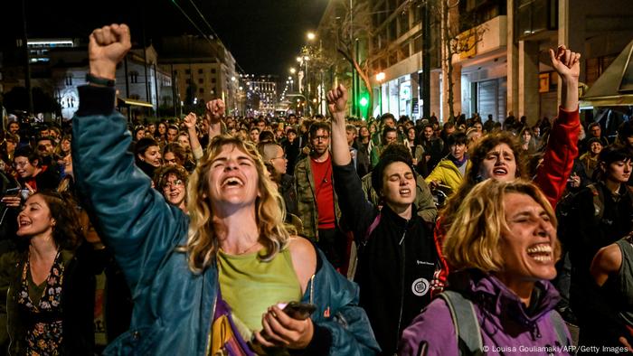 Hunderte Frauen stehen mit geschlossenen Augen in einer Straße in Athen und strecken zum Teil ihrer Fäuste in die Höhe