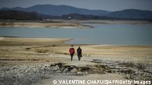 Two women walk towards the partially dry Lake Montbel, south-western France, on February 21, 2023. - France has matched its record dry spell of 31 days without significant rainfall, the country's weather service said February 21, amid concerns over water reserves in parts of Europe still reeling from last year's severe drought. With rainfall over the entire country of less than one millimetre a day since January 21, weather service Meteo France said the absence of precipitation equals the record set in spring 2020. (Photo by Valentine CHAPUIS / AFP) (Photo by VALENTINE CHAPUIS/AFP via Getty Images)