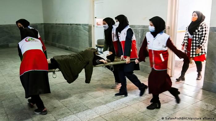 Bewusstlose Schülerin auf einer Trage mit Klassenkameradinnen in Teheran