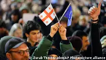 A young woman holds a Georgian national flag and an EU flag during a rally against a draft law aimed at curbing the influence of foreign agents near the Georgian parliament building in Tbilisi, Georgia, Thursday, March 9, 2023. Following days of massive protests, Georgia's governing party said Thursday it would withdraw draft legislation that opponents warned would stifle dissent and curtail media freedoms, ushering in Russian-style repression. (AP Photo/Zurab Tsertsvadze)