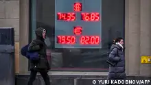 Pedestrians walk past a board at a currency exchange office in Moscow on February 16, 2023, as the Russian ruble dropped to its weakest marks against US dollar and euro since late April. (Photo by Yuri KADOBNOV / AFP)