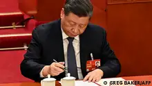 China's President Xi Jinping signs a presidential order to appoint Li Qiang as premier during the fourth plenary session of the National People's Congress (NPC) at the Great Hall of the People in Beijing on March 11, 2023. (Photo by GREG BAKER / POOL / AFP)