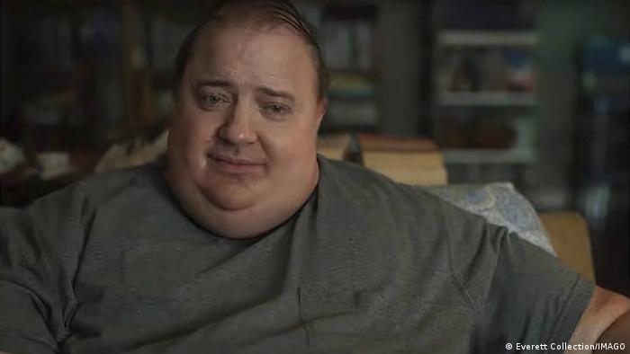 In einer Szene des Films The Whale sitzt ein stark übergewichtiger Mann auf einer Couch.