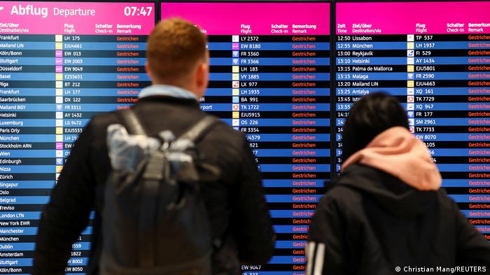 Dos personas miran los vuelos cancelados en una pantalla del aeropuerto de Berlín.