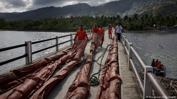 Mitarbeiter der philippinischen Küstenwache mit Ölsperren, mit denen der Ölteppich eingedämmt werden soll