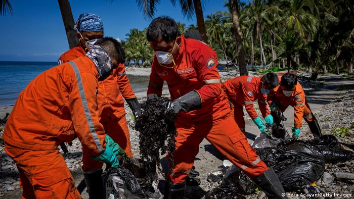 Helfer transportieren an dem betroffenen Küstenabschnitt der Provinz Oriental Mindoro ölverdreckte Meerespflanzen ab 