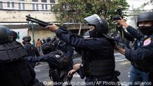 Police in riot gear aim a rubber bullet shotgun over protesters trying to march to the Asia-Pacific Economic Cooperation APEC summit venue, Friday, Nov. 18, 2022, in Bangkok, Thailand. (AP Photo/Wason Wanichakorn)