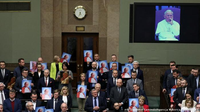 Abgeordnete im polnischen Sejm halten während einer Debatte am 9.03.23 Bilder von Johannes Paul II. hoch 