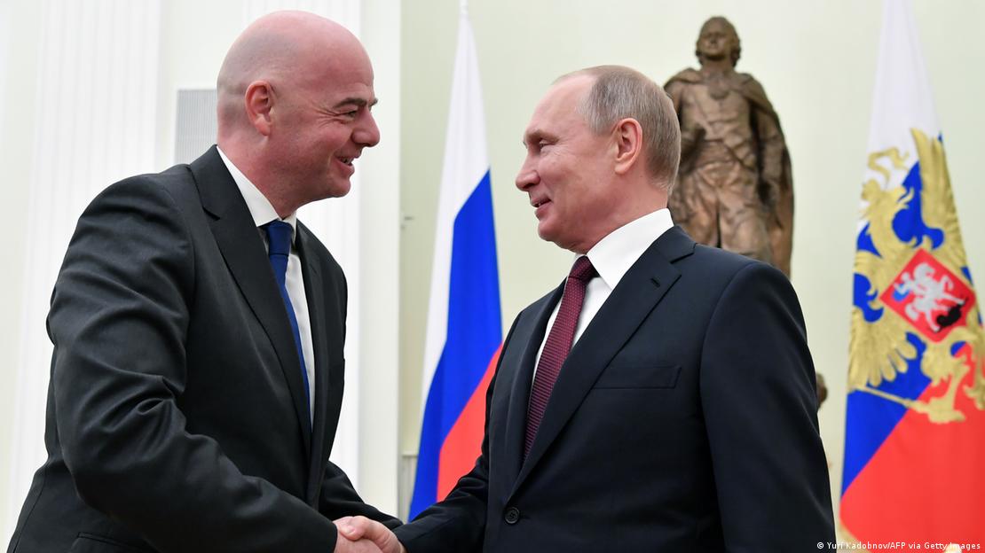 Infantino saluda a Putin. Detr&aacute;s, banderas.