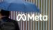 A man walks past the Meta logo carrying an umbrella A man walks past the Meta logo carrying an umbrella