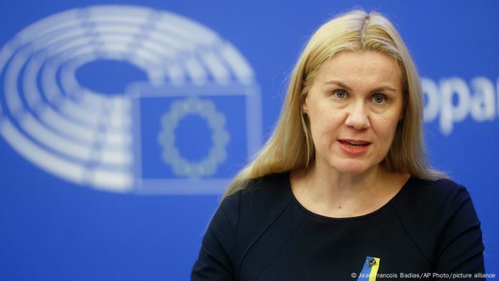 La política, con un pin de apoyo a Ucrania, con un logo de la UE al fondo.