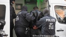 15.03.2023+++ Polizisten führen bei einer Razzia in Berlin einen Mann ab. Mit einer großen Razzia ist die Polizei in Berlin und Sachsen-Anhalt gegen eine Bande mutmaßlicher Schleuser vorgegangen. Mehr als 20 Wohnungen und Büros vor allem in Berlin wurden am Mittwochmorgen durchsucht, wie ein Sprecher der Bundespolizei sagte. Fünf Männer wurden festgenommen, vier davon in Berlin und einer in Halle. Insgesamt wird gegen 18 Verdächtige ermittelt. Die Bande soll Menschen aus der Türkei und dem Irak nach Deutschland geschmuggelt haben.