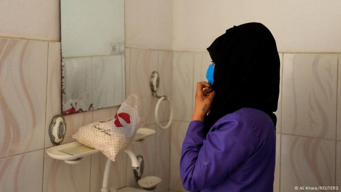 Eine junge afghanische Frau richtet ihr Kopftuch vor einem Spiegel.