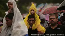 Männer tragen Kinder auf ihren Schultern, als sie zusammen mit zahlreichen Migranten unter dem Regen zu Fuß in Richtung Norden aufbrechen. Nach lokalen Medienberichten sind darunter viele Venezolaner, die aus ihrem Land ausgewandert sind.