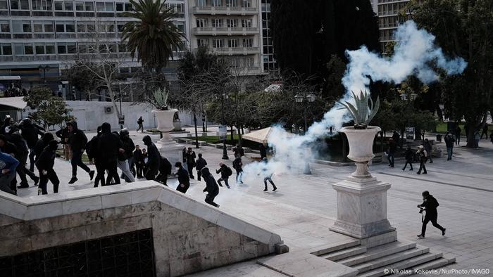 Hooded demonstrators running away in a square