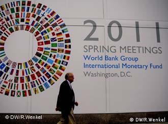 Ein Passant geht am Logo des Frühjahrstreffens von IWF und Weltbank 2011 vorbei (Foto: DW)