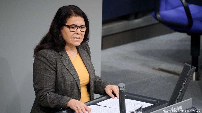 Eine Frau mit langen dunklen Haaren und Brille steht an einem Rednerpult, dasa die Aufschrift Bundestag trägt
