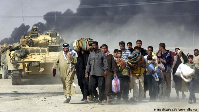 Menschen fliehen aus Basra im Jahr 2003 im Hintergrund schwarzer Rauch und Panzer