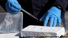 A narcotics officer conducts a chemical analysis to confirm the purity of a cocaine block, in Cayambe, Ecuador, Friday, March 3, 2023. The destruction of drugs seized in Ecuador has been sped up by the application of a novel procedure that transforms cocaine into cement or concrete, although it is not used for construction, but remains in subway cells with other waste. (AP Photo/Dolores Ochoa)