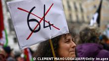 A protester, holding a placard with a crossed 64-year-old, participates in a demonstration in Marseille, southern France, on March 18, 2023, two days after the French government pushed a pensions reform through parliament without a vote, using the article 49.3 of the constitution. - France on March 18 braced for a weekend of protests, after a second night of unrest sparked by the French president imposing without a parliament vote an unpopular pension overhaul, that includes raising the retirement age from 62 to 64. (Photo by CLEMENT MAHOUDEAU / AFP) (Photo by CLEMENT MAHOUDEAU/AFP via Getty Images)