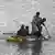 Cinco crianças remam em um bote improvisado em uma área alagada do Paquistão.