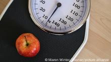 Red apple on an analogue personal scale on a wooden floor, concept for healthy eating, lose weight diet and fitness, high angle view from above, copy space