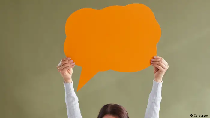Young person holding up an orange-colored speech bubble.