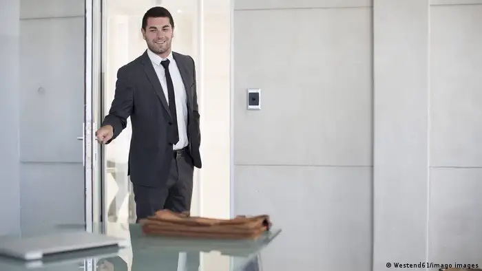 Man opening office door and smiling.