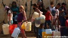 Menschen stehen mit Kanistern und Gefäßen Schlange um Wasser zu bekommen. In vielen Haushalten im Land gibt es kein fließendes Wasser mehr. Die Wasserversorgung funktionieren teils nicht mehr. Die Coronavirus-Pandemie verschlimmert die Situation noch. +++ dpa-Bildfunk +++