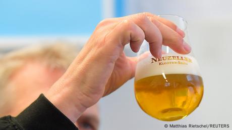 Jemand hält ein Glas Bier mit der Aufschrift „Neuzeller Kloster-Bräu“ hoch. (Quelle: Matthias Rietschel/REUTERS)