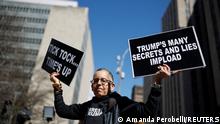 Anti-Trump demonstrator Laurie Arbeiter holds placards outside Manhattan Criminal Court, after a message was posted on the Truth Social account of former U.S. President Donald Trump stating that he expects to be arrested on Tuesday, and called on his supporters to protest, in New York City, U.S. March 21, 2023. REUTERS/Amanda Perobelli