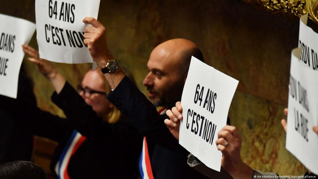 Members of National Assembly parliamentary group La France Insoumise (LFI) and left-wing coalition NUPES (New People's Ecologic and Social Union) hold signs reading '64 is a no.'