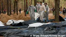 September 19, 2022**Forensics carry body bags in a forest near Izyum, eastern Ukraine, on September 19, 2022, where Ukrainian investigators have uncovered more than 440 graves after the city was recaptured from the Russians, bringing fresh claims of Russian atrocities. - The Kremlin denied its forces were responsible for large-scale killings and accused Kyiv of fabricating its discoveries of mass graves in recaptured territory. (Photo by SERGEY BOBOK / AFP) (Photo by SERGEY BOBOK/AFP via Getty Images)