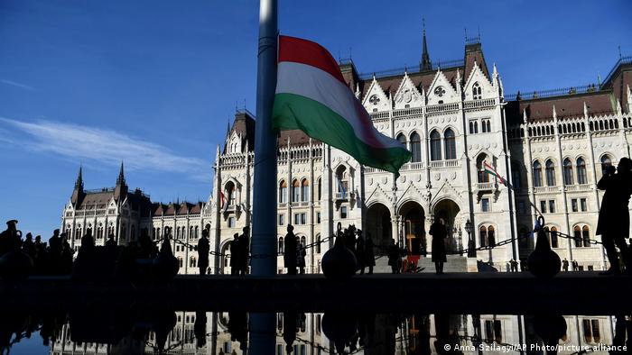 Exterior view of the Hungarian Parliament in Budapest with the Hungarian flag in the foreground